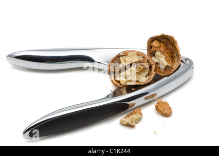 Cracking walnuts with nutcracker over white background Stock Photo