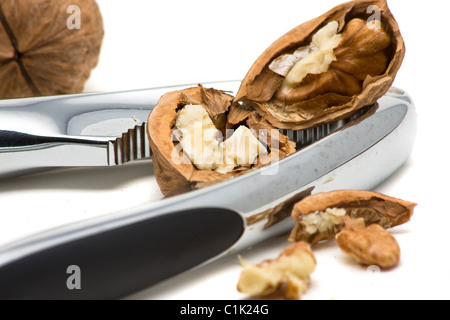 Cracking walnuts with nutcracker over white background Stock Photo