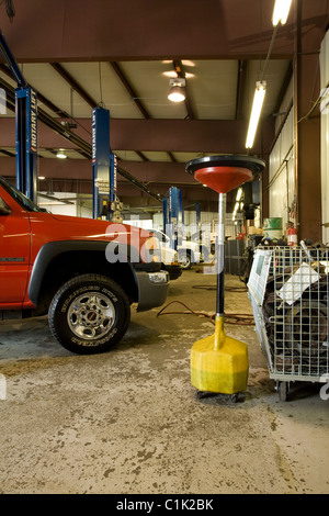 Pan used for draining oil from a vehicle sits in a large auto repair facility at an auto dealer. Stock Photo