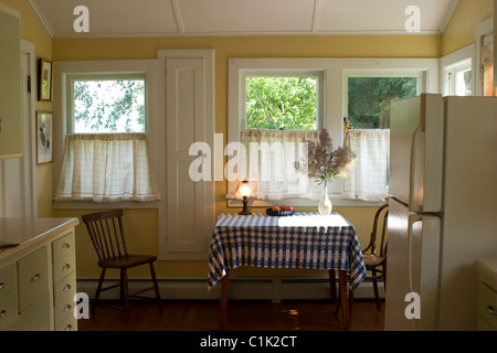 A small country kitchen is bathed in sunlight in the Berkshires of Massachusetts. See tall narrow door for folding ironing board Stock Photo