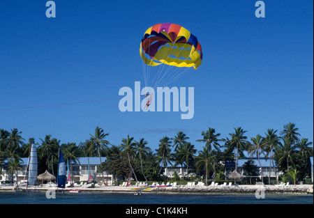 Towed by a boat, a parasailer soars with a colorful parachute above Cheeca Lodge, a Florida Keys oceanfront resort in Islamorada, Florida, USA. Stock Photo