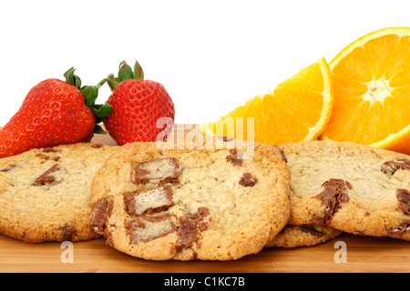 Chocolate chip cookies arranged on a wooden board and decorated with strawberries and oranges. White background - close-up Stock Photo