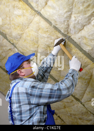Worker thermally insulating a house attic using mineral wool Stock Photo