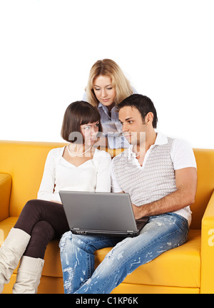 Three friends sitting on sofa with laptop computer Stock Photo