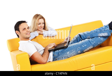 Happy young man and woman sitting together on yellow sofa; isolated on white Stock Photo