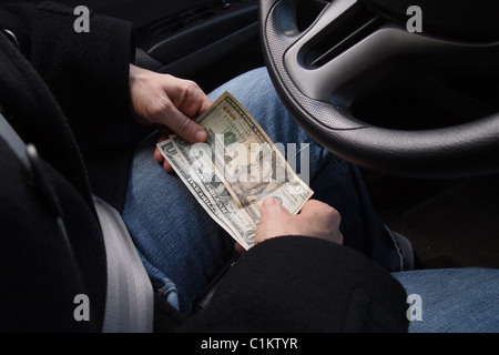 Woman sits in her car holding money to pay for gas while her car is being fueled, March 19, 2011, Katharine Andriotis Stock Photo