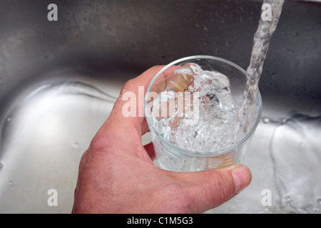 Man filling a glass with water from a kitchen tap. Stock Photo