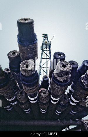 Oil rig drill pipes stacked with oil industry workers in the background ...