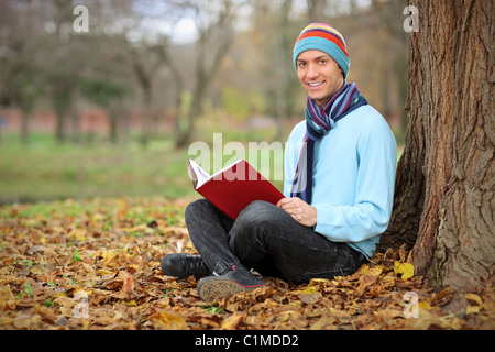 Young smiling man reading a book in the city park in Skopje