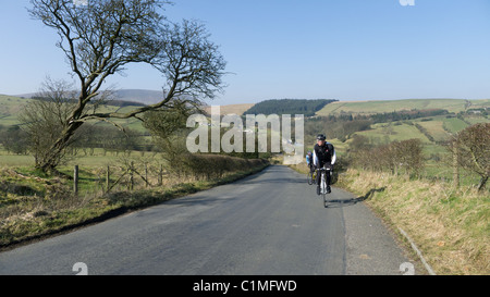 Cycling up a steep hill in early spring, Lancashire Stock Photo