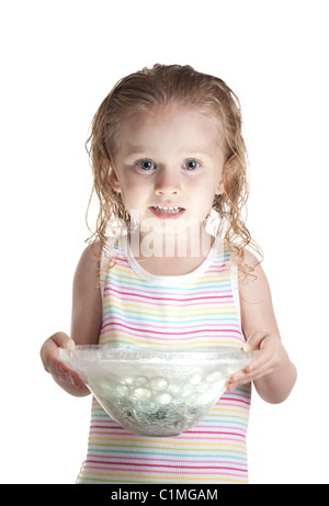 A nervous girl holding a glass bowl. The bowl has a ball of light inside of it. The light is glowing onto her face. Stock Photo