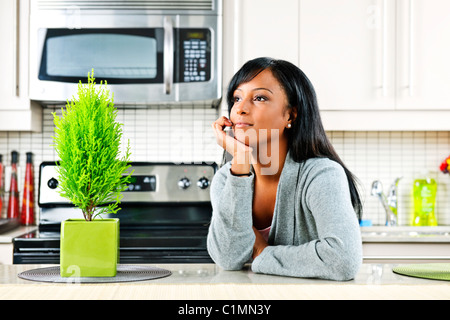 Thoughtful black woman in modern kitchen interior Stock Photo