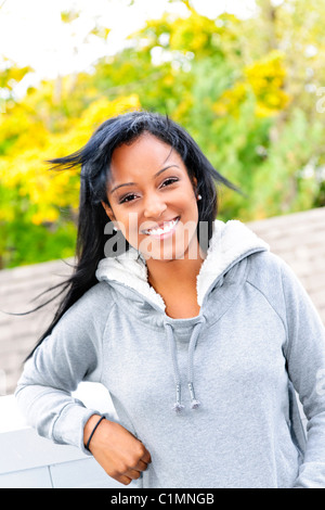 Smiling young black woman outside in casual hoodie on windy day Stock Photo