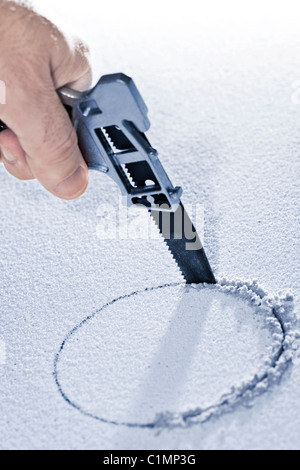 Handsaw cutting circular hole in ceiling tile Stock Photo