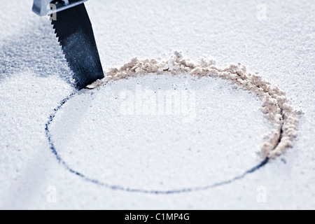 Handsaw cutting circular hole in ceiling tile Stock Photo