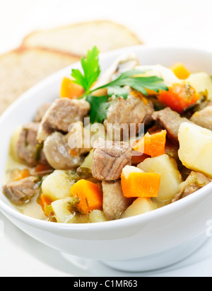 Bowl of hearty beef stew with vegetables served with rye bread Stock Photo
