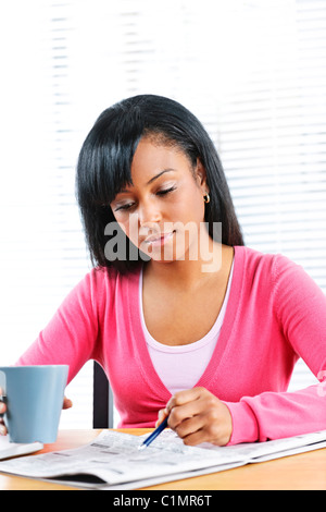 Young black female student looking in newspaper for job Stock Photo