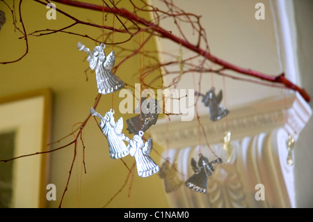 Tin angel christmas decorations hanging from a branch Stock Photo