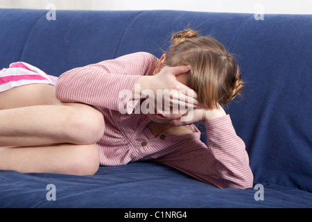 sad little girl lying on sofa Stock Photo