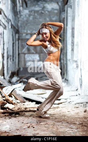 Young woman dancing on industrial background. Stock Photo