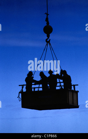 Construction workers descend from Transamerica pyramid construction site at sunset in bucket of crane Stock Photo