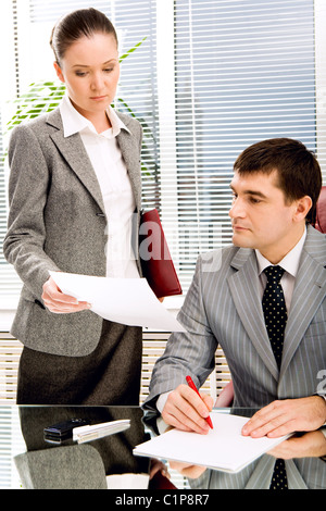 Photo of confident leader looking at documents being shown by his secretary Stock Photo