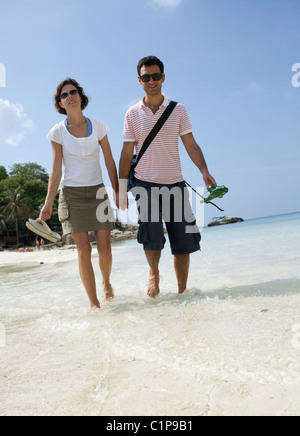 Mid adult couple holding hands and walking on beach Stock Photo