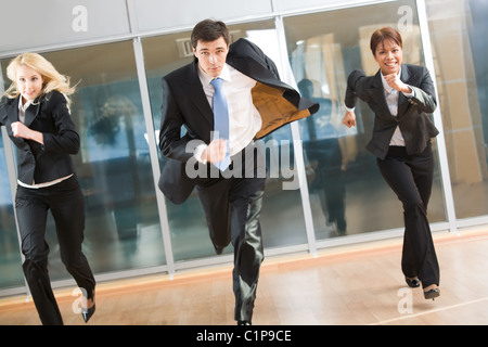 Portrait of hurrying people in suits running forwards for work with optimistic expression Stock Photo