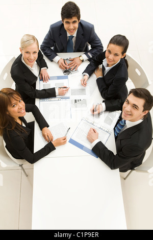 Several white collar workers looking upwards at camera with happy smiles Stock Photo