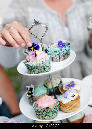 Hand reaching for muffins decorated with fresh flowers Stock Photo