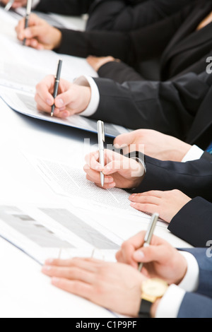 Image of row of people hands writing on papers at seminar Stock Photo
