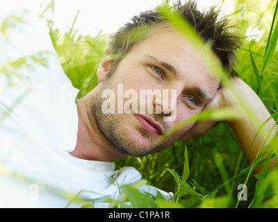 Young man lying on grass and looking away Stock Photo