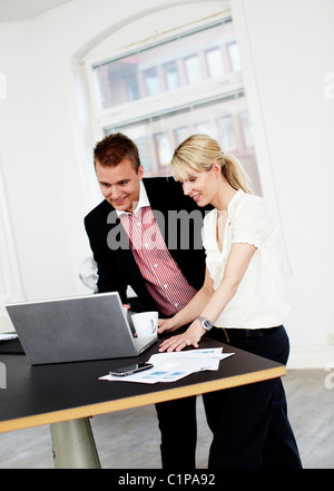Businessman and woman using laptop in office Stock Photo