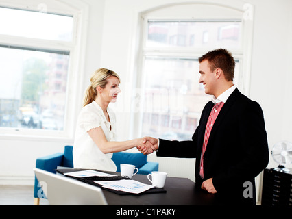 Businessman and woman shaking hands in office Stock Photo