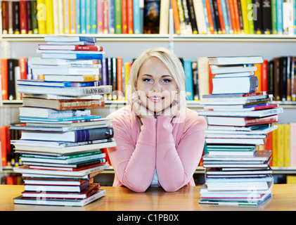 Young woman surrounded by books in library Stock Photo
