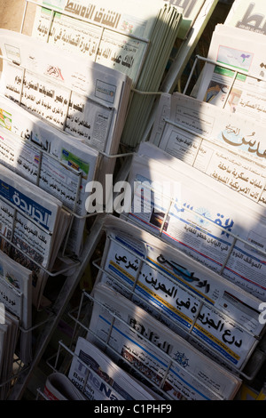 The shadow of a passing pedestrian is cast over Arabic newspapers headlines on sale in a London shop. Stock Photo