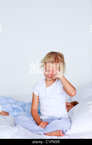 Sweet little girl sitting on a bed Stock Photo