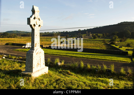 Republic of Ireland, Boyne Valley, Celtic Cross in graveyard of St Feichin's Church, Fore Abbey in distance. Stock Photo