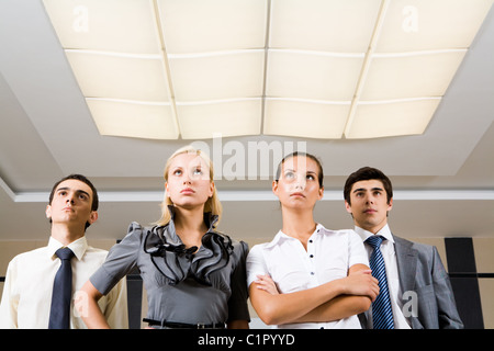 Several confident employees standing in row and looking upwards seriously Stock Photo