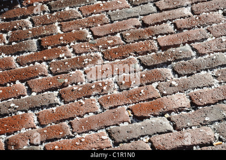 a red brick walkway covered in salt in bright sunlight Stock Photo