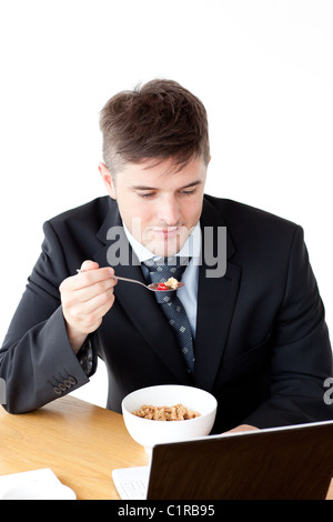 Young businessman using a laptop while having breakfast Stock Photo