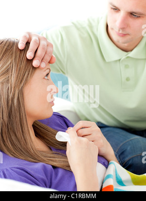 Close-up of worried man feeling the temperature of his unhealthy girlfriend in the living room Stock Photo