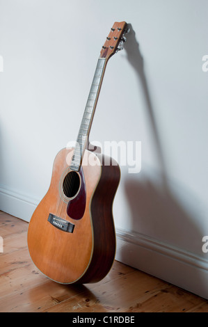 6 string acoustic guitar (Yamaha) leaning against a white wall. Stock Photo