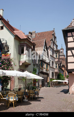 Riquewihr, Alsace, Haut-Rhin, France, Europe. Pavement cafes and old buildings on narrow cobbled street in medieval town Stock Photo