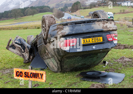 A BMW car crashed on its roof in the middle of a field after leaving the road at high speed on the A66 near Keswick Cumbria UK Stock Photo