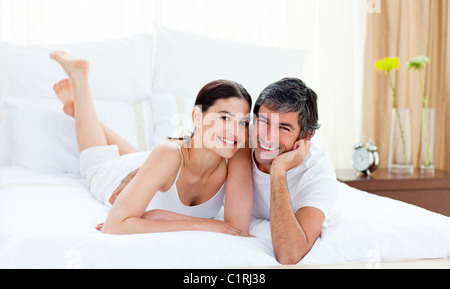 Loving couple cuddling lying on their bed Stock Photo