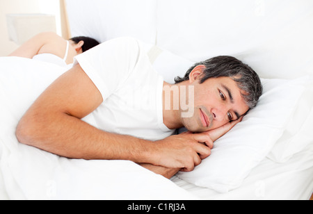 Upset man lying in his bed Stock Photo