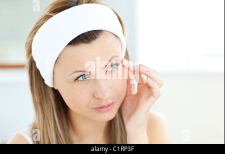 Young woman putting creme on her face Stock Photo