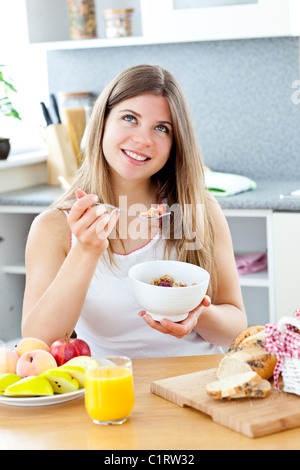 Glowing brunette woman eating cereals with raspberrie in the kitchen Stock Photo