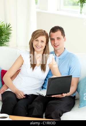 Enthusiastic couple using laptop smiling at the camera Stock Photo